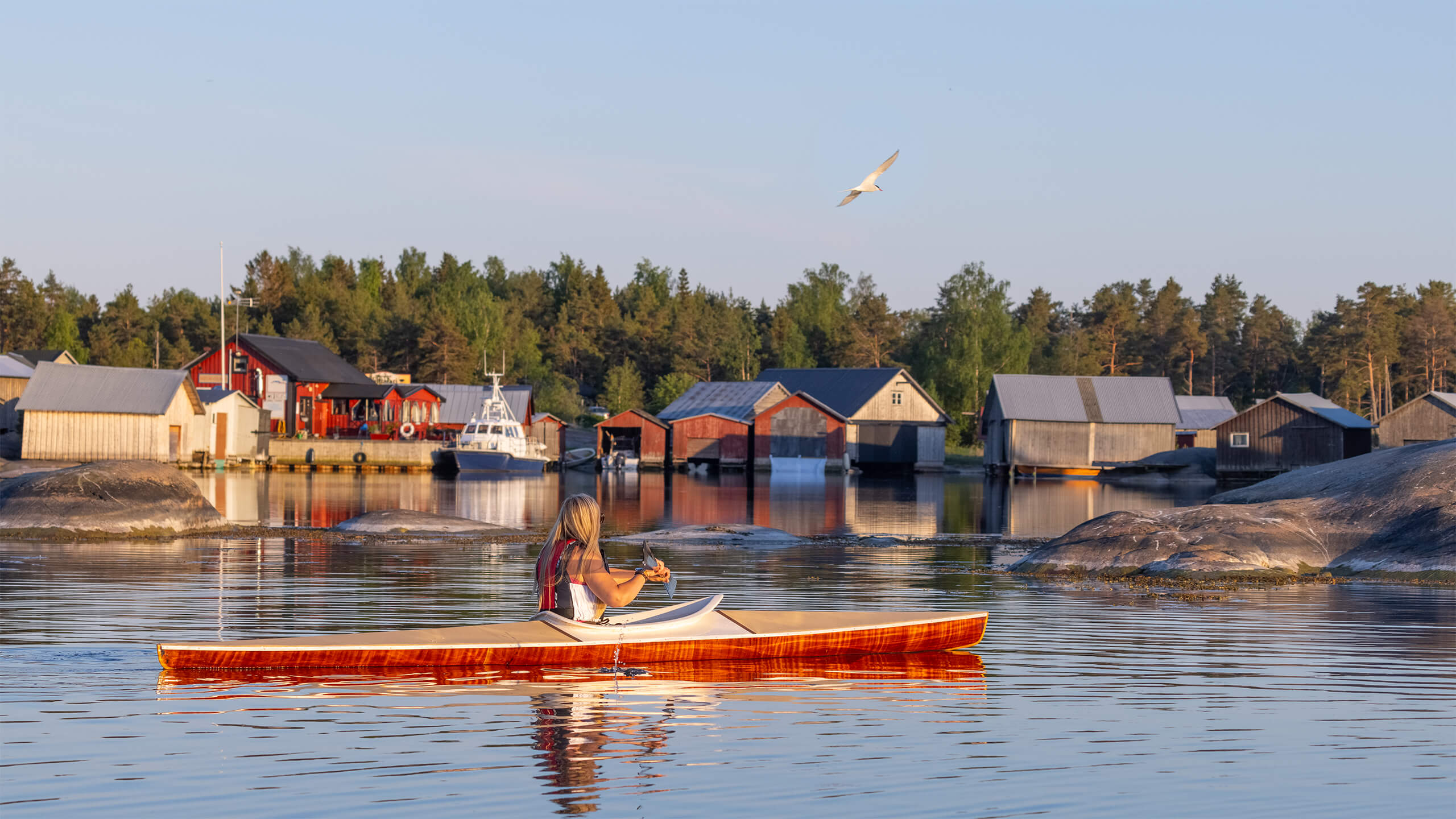 Person som paddlar kajak bland båthus i Käringsund